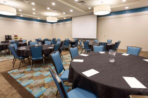 A conference room with round tables, blue chairs, and a projector screen. - Drury Inn Pikes Peak Colorado Springs (Colorado Springs)