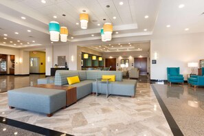 A spacious lobby with a sectional sofa, a coffee table, and teal armchairs. - Drury Inn Pikes Peak Colorado Springs (Colorado Springs)