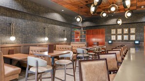 L'intérieur d'un restaurant avec des banquettes, des tables et des luminaires suspendus.