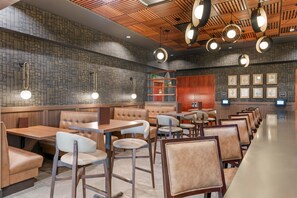 L'intérieur d'un restaurant avec des banquettes, des tables et des luminaires suspendus.