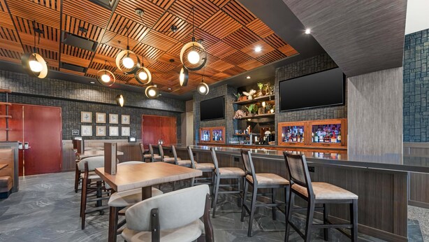 Ein Restaurant mit Holzbalkendecke, Bar, Sitzgelegenheiten und an Wänden befestigten Fernsehern.