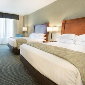 A hotel room with two beds, a headboard, bedside lamps, and a window with curtains. - Drury Inn & Suites Colorado Springs (Colorado Springs)
