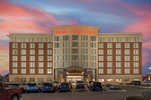 Et hotel med et tydeligt skilt, flere parkeringspladser og en godt oplyst indgang.