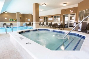 A hotel pool area with a hot tub, seating area, and a sign indicating no diving.
