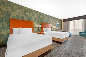A hotel room with two beds, a large window with curtains, a green forest-themed wall, and a blue chair. - Drury Inn Pikes Peak Colorado Springs (Colorado Springs)