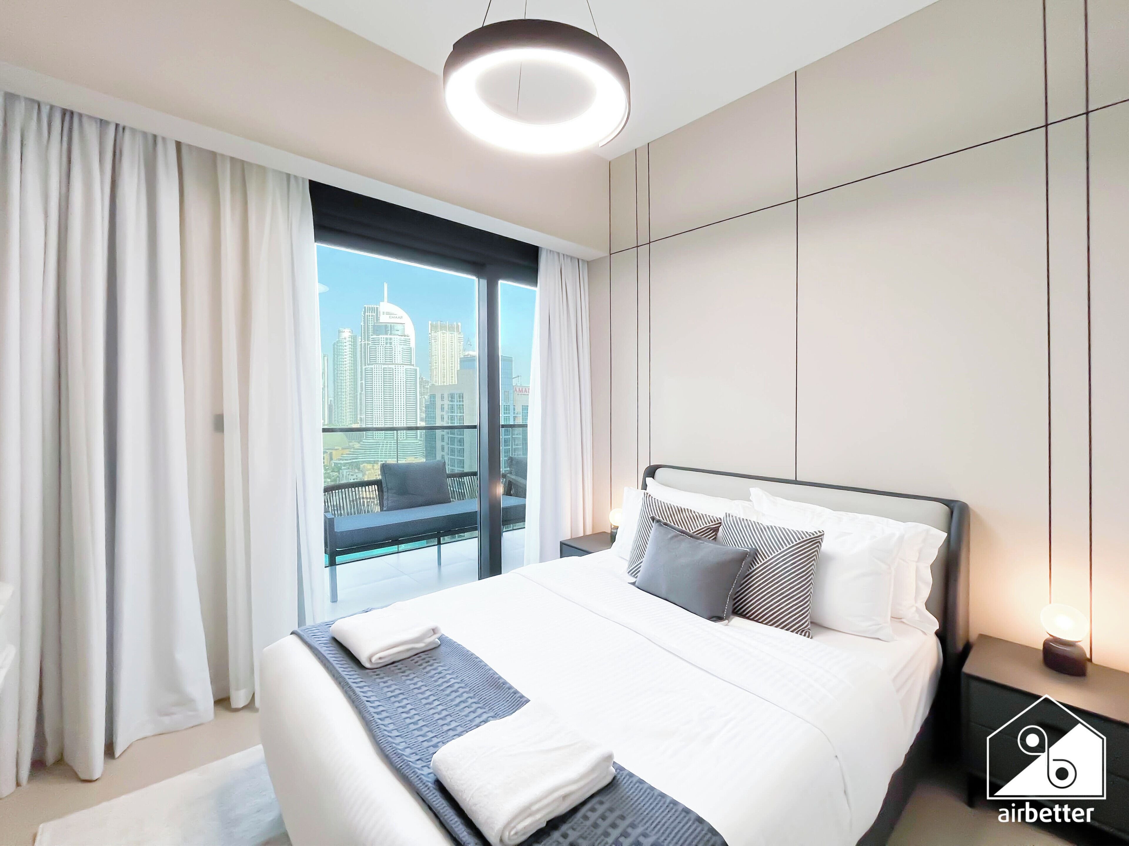 A modern hotel room with a large bed, a city view, and a balcony.