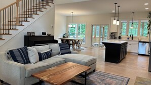 A spacious living room with a grey sofa, wooden coffee table, and a staircase.