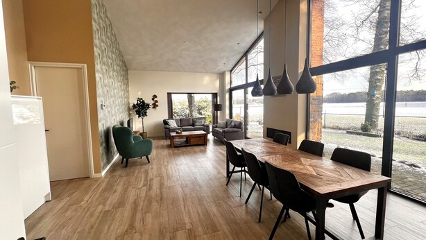 Amplia sala de estar con una gran mesa de comedor de madera, un sillón verde y un sofá.