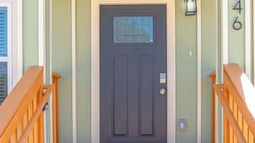 A front entrance with a dark door, a welcome mat, and a wooden staircase leading up.