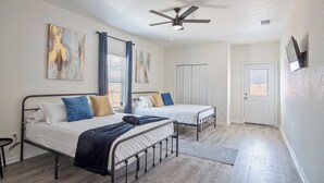 Ein Schlafzimmer mit zwei Betten, einem Deckenventilator und Blick ins Freie.