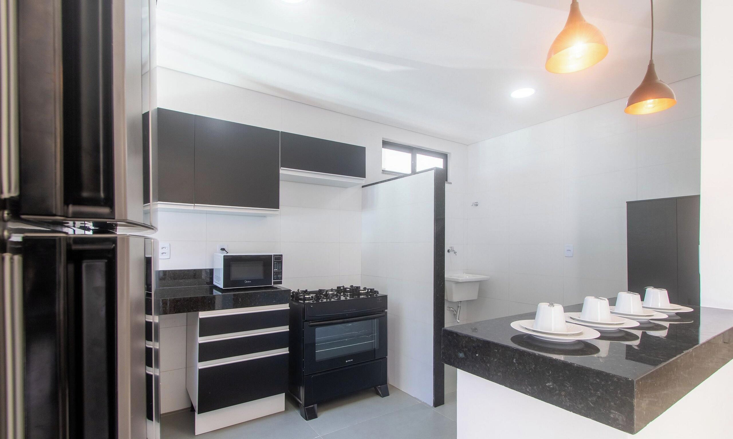A modern kitchen with a microwave, oven, and black cabinets.