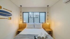 Une chambre à coucher comprenant un lit, deux tables de chevet, une fenêtre avec vue et deux lampes fixées au mur.