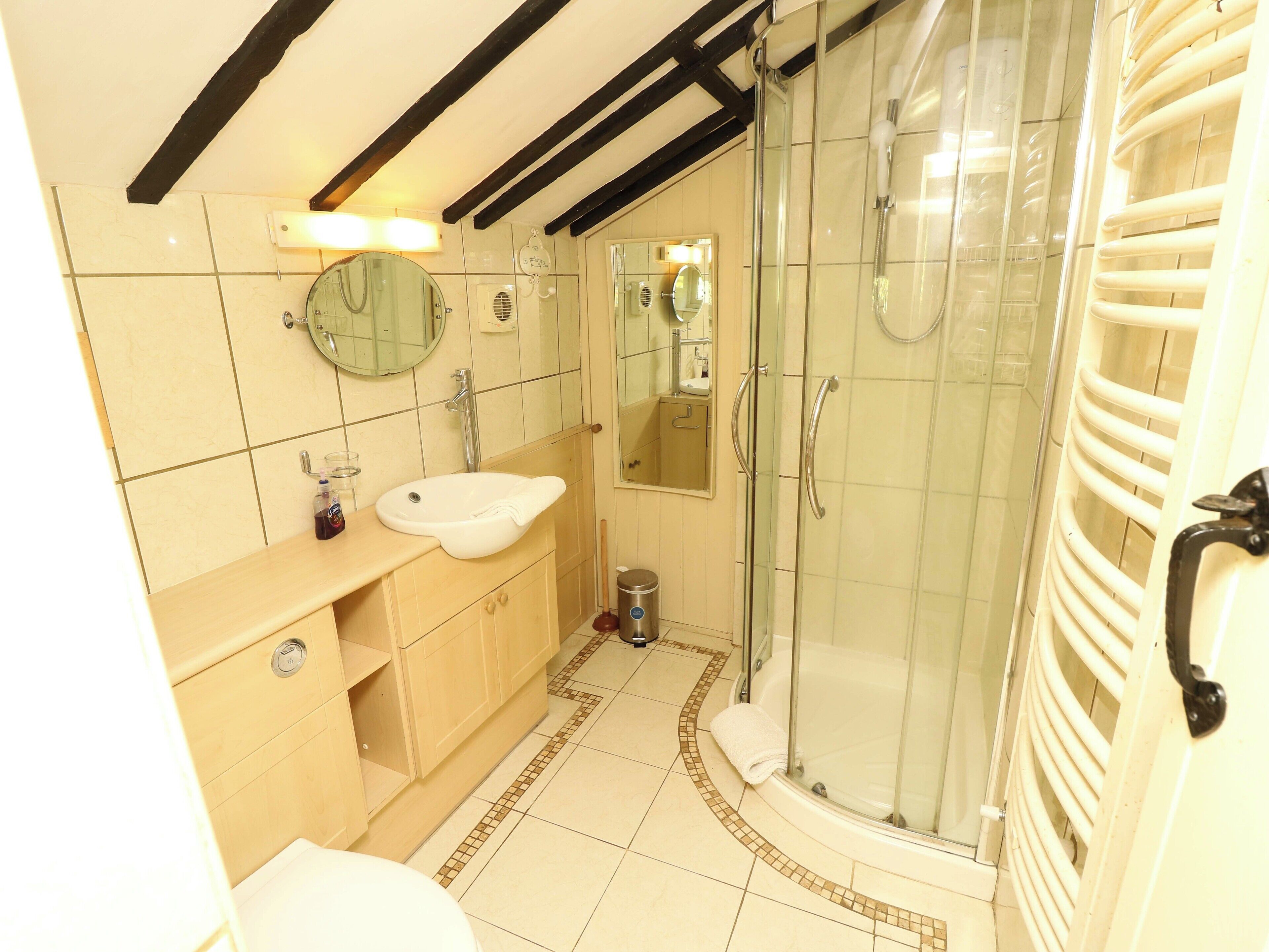 Een badkamer met een wastafel, spiegel en douche.
