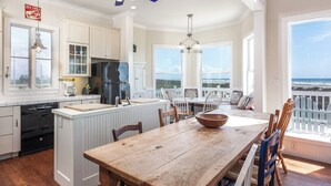 A spacious kitchen with a large island, white cabinetry, and a view of the ocean. - Breakers Pointe by Ryson Vacation Rentals (Galveston)