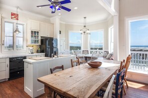 A spacious kitchen with a large island, white cabinetry, and a view of the ocean. - Breakers Pointe by Ryson Vacation Rentals (Galveston)