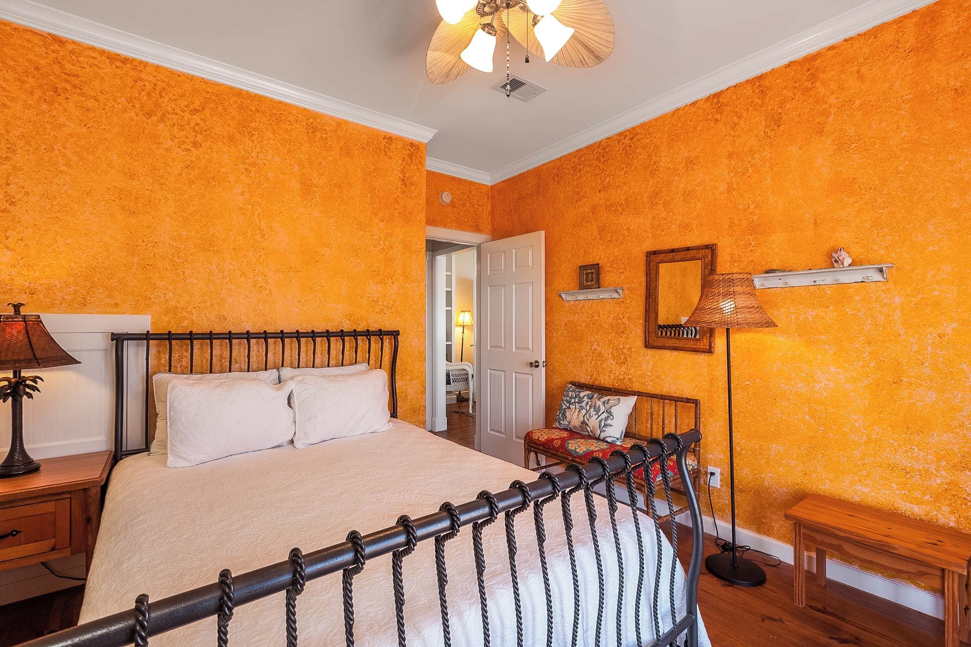 Un dormitorio con cama, mesita de noche, lámpara y una silla.