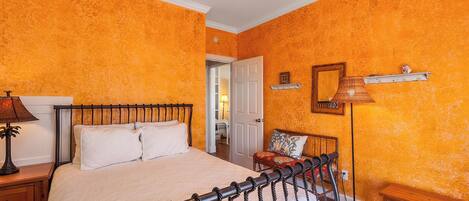 Un dormitorio con cama, mesita de noche, lámpara y una silla.
