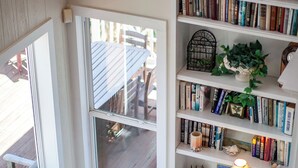 A cozy reading nook with a built-in bench, a bookshelf filled with books, and a small table with a lamp. - Breakers Pointe by Ryson Vacation Rentals (Galveston)