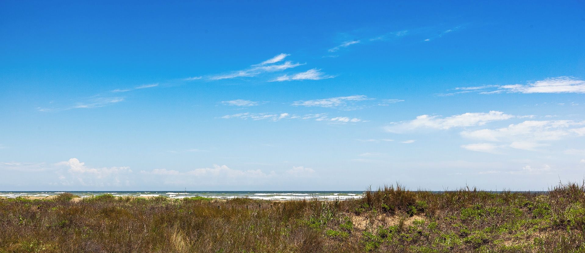 Eine Küstenlandschaft mit klarem Himmel und Blick auf das Meer.