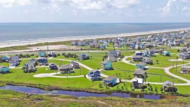 A coastal residential area with houses, a beach, and a road. - Breakers Pointe by Ryson Vacation Rentals (Galveston)