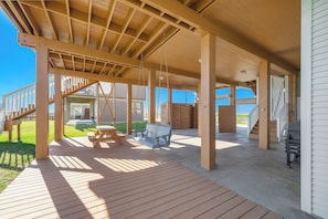 A covered outdoor area with wooden beams, a picnic table, a bench, and a barbecue grill. - Beach Heaven by Ryson Vacation Rentals (Galveston)