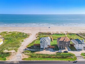 A coastal residential area with houses, a beach, and a clear view of the ocean. - Beach Heaven by Ryson Vacation Rentals (Galveston)