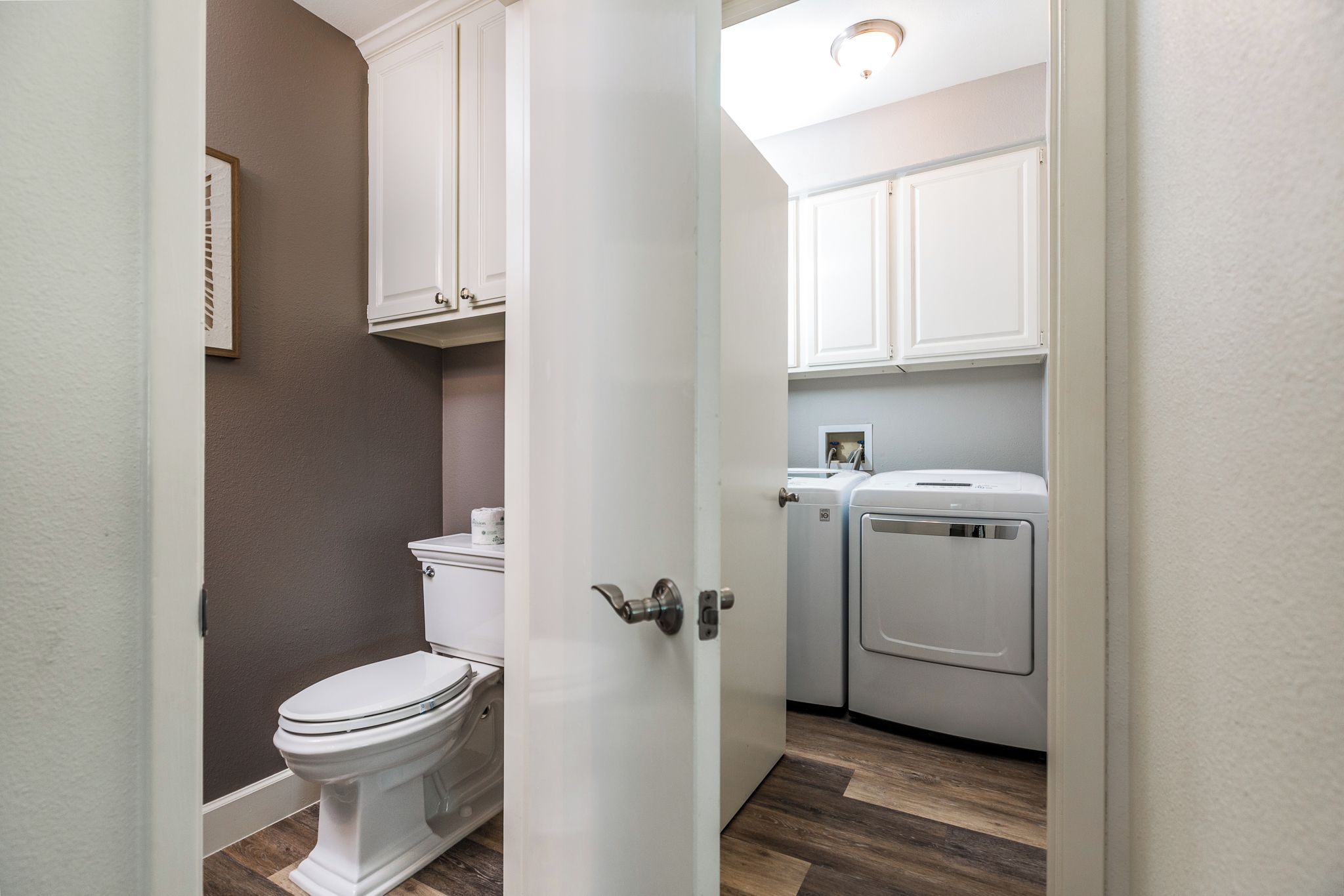 A compact bathroom with a toilet, a washing machine, and a dryer.