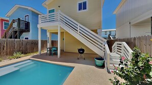 Ein zweistöckiges Haus mit überdachter Terrasse, Pool und Grill.
