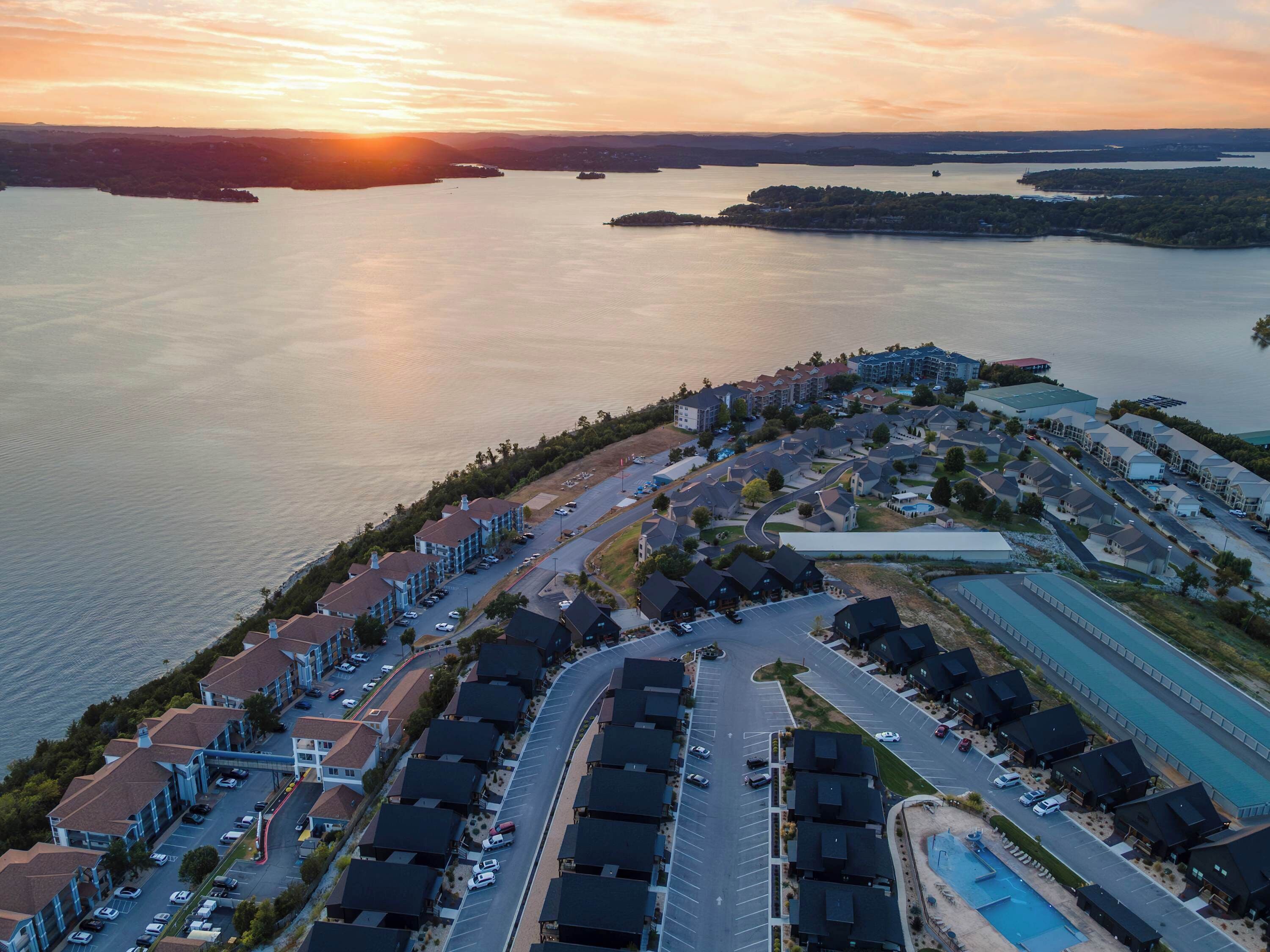 Vista aérea de una zona residencial costera con varios edificios, carreteras y un puerto deportivo.
