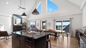 A spacious kitchen with a central island, large windows, and a high ceiling.