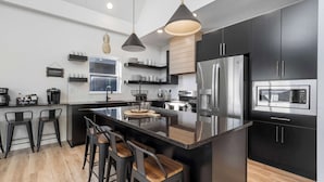 A modern kitchen with black cabinets, stainless steel appliances, and a central island with bar stools.