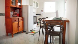 Une cuisine avec des meubles de rangement en bois, un réfrigérateur blanc et une table à manger avec des chaises.