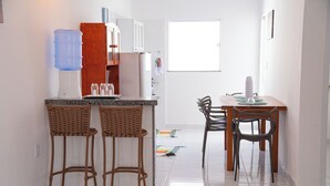 Une cuisine moderne avec un coin bar, des meubles blancs et une grande fenêtre.