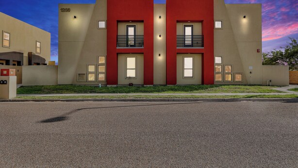 Een modern gebouw met twee rode gedeelten en beige muren, voorzien van balkons en grote ramen.