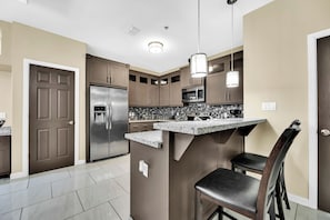 A modern kitchen with a central island, stainless steel appliances, and pendant lighting.