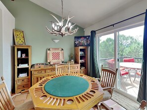 A dining area with a round table, chairs, a chandelier, and a view of the outdoors. - Eagle's Nest by Ruidoso Vacation Rentals (Ruidoso)