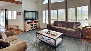 A spacious living room with a large TV, comfortable seating, and a view of the outdoors.