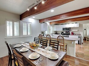 A dining area with a wooden table set for four, white cabinets, and a kitchen in the background. - Eagle's Nest by Ruidoso Vacation Rentals (Ruidoso)