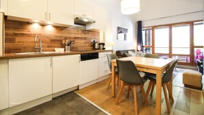 Une cuisine moderne avec des meubles blancs, un plan de travail en bois et un coin repas comprenant une table et des chaises.
