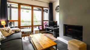Un salon avec un canapé, une table en bois, un téléviseur et une cheminée.