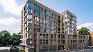 Ein modernes, mehrgeschossiges Gebäude mit einer rasterartigen Fassade, großen Fenstern und einem flachen Dach.