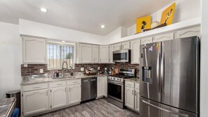 A modern kitchen with white cabinets, stainless steel appliances, and a brick backsplash.