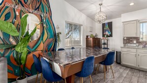 A modern kitchen with a marble countertop, blue chairs, and a chandelier.