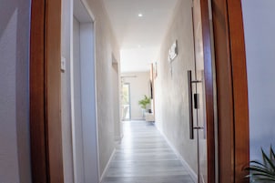 Um corredor com portas de madeira, uma planta em vaso e piso claro.