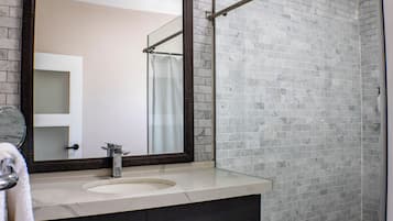 Bany amb un mirall gran, un lavabo i una zona de dutxa.