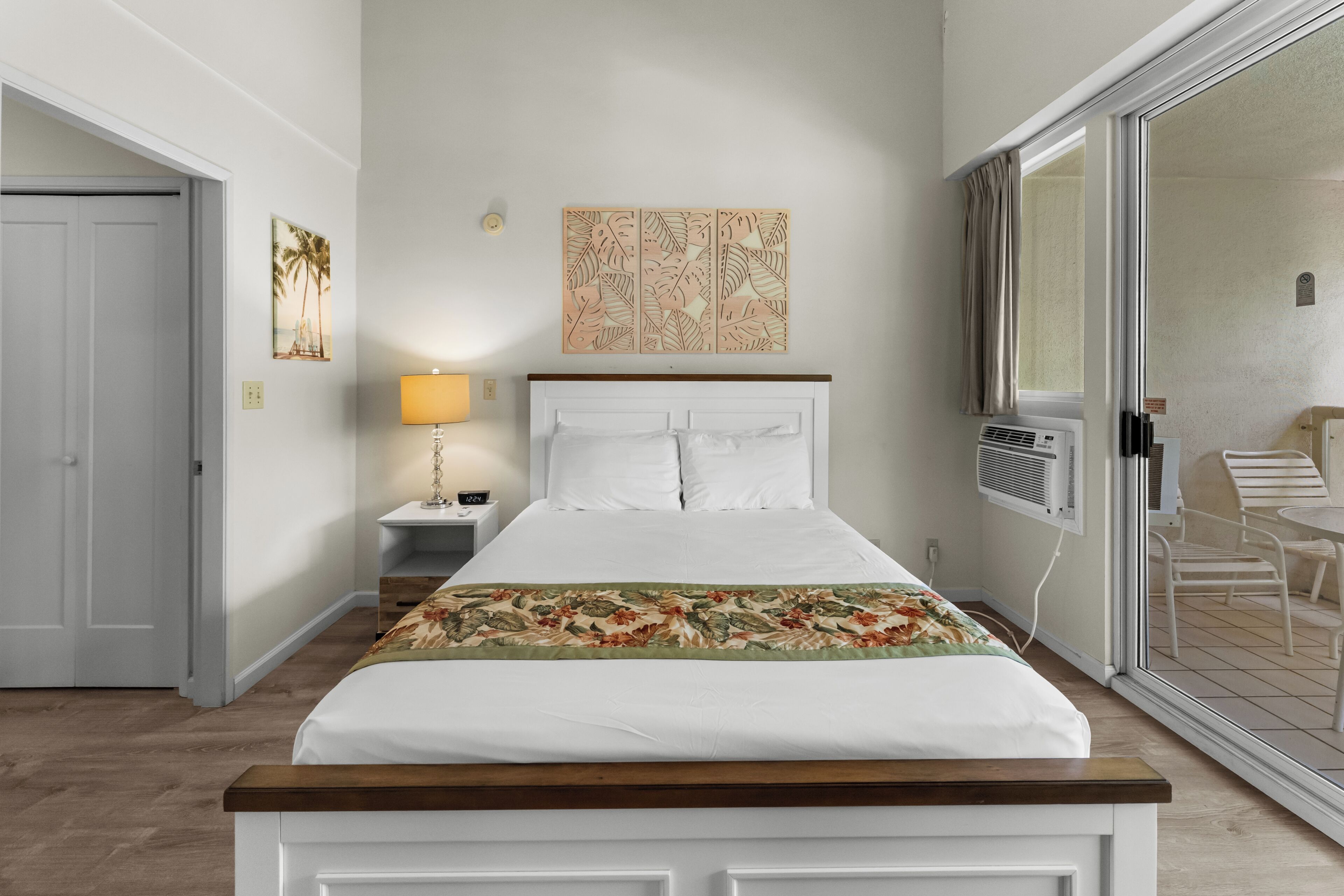 A neatly arranged bedroom with a bed, a nightstand, a lamp, and a window with a view of the outside.