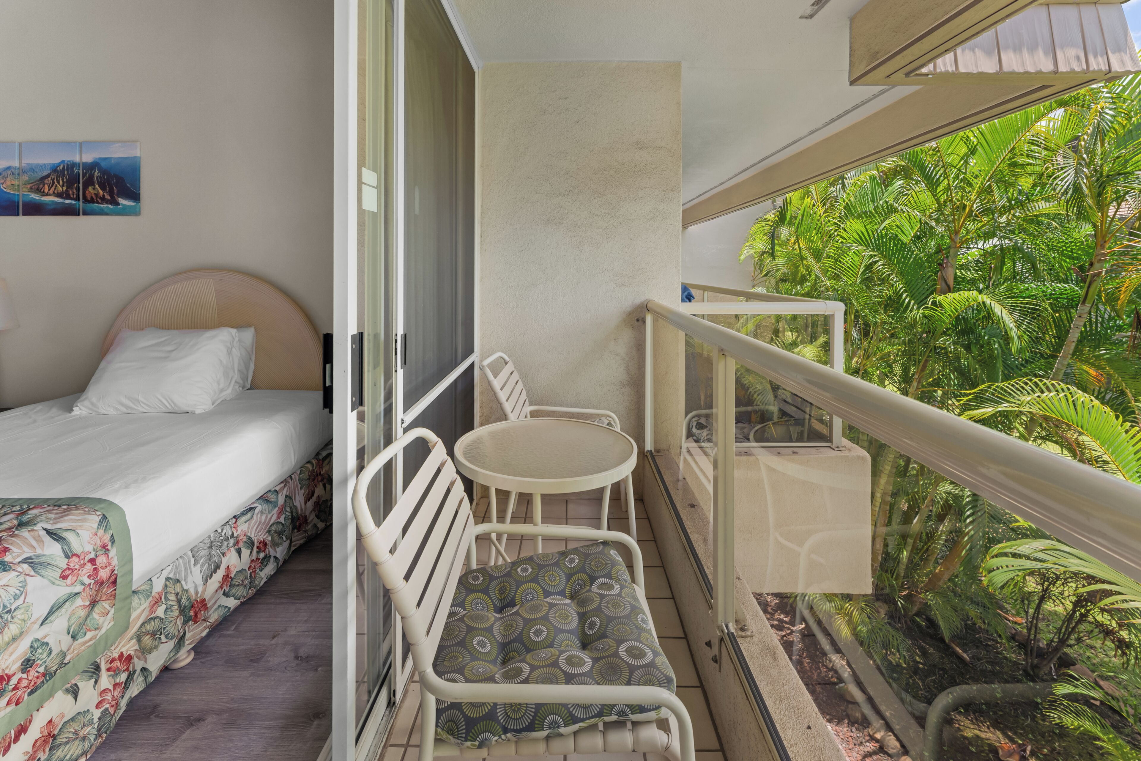 A balcony with a bed, a chair, and a small table.