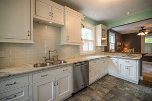 A kitchen with white cabinets, a stainless steel dishwasher, and a marble countertop.