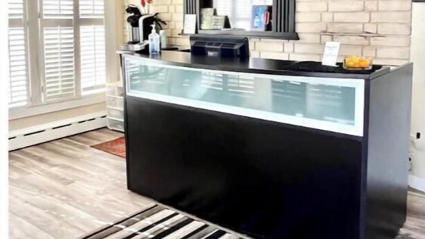 A reception desk with a black counter, a glass partition, and a brick wall backdrop.