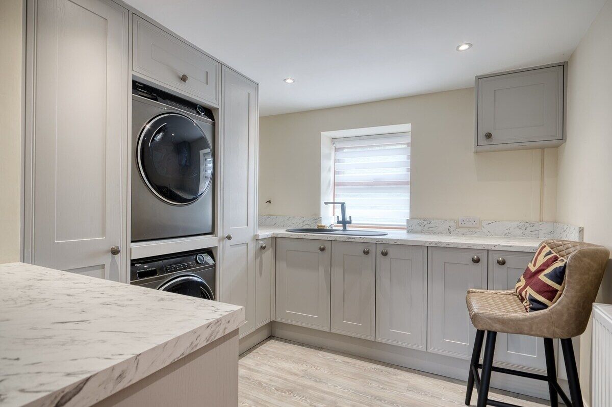 A modern kitchen with built-in appliances, a marble countertop, and a bar stool.